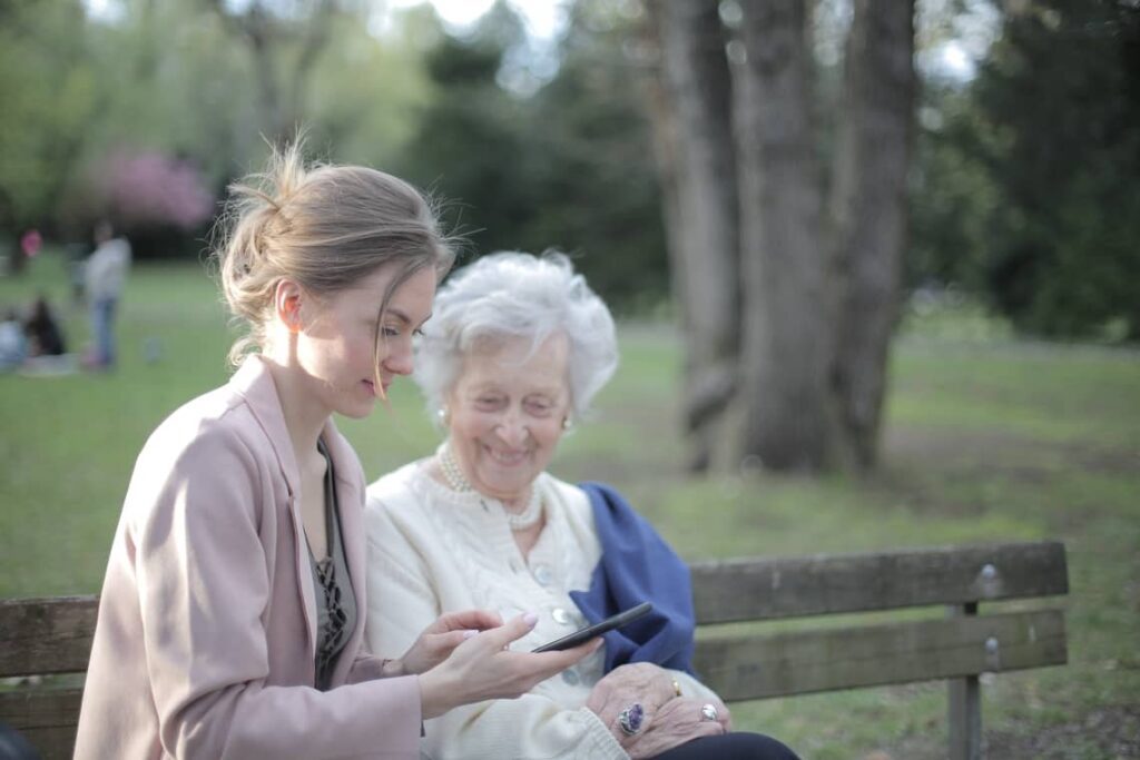 A woman and an old lady looking at something on their phone.