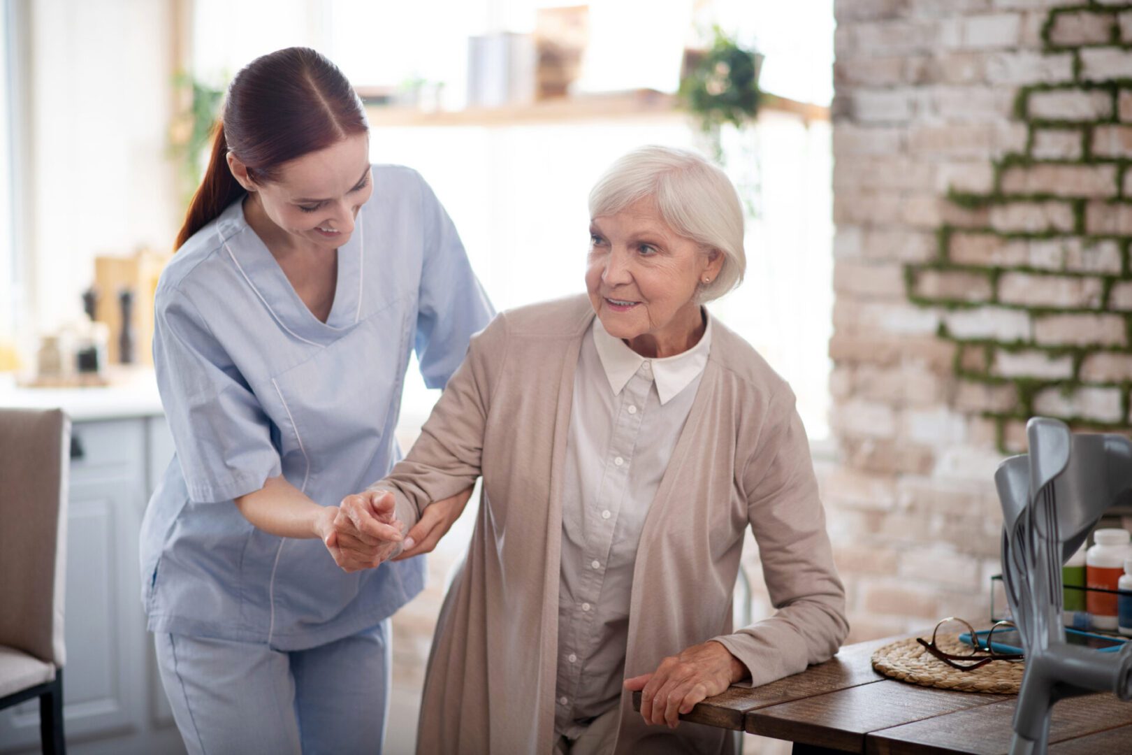 Caregiver assisting elderly woman at home.