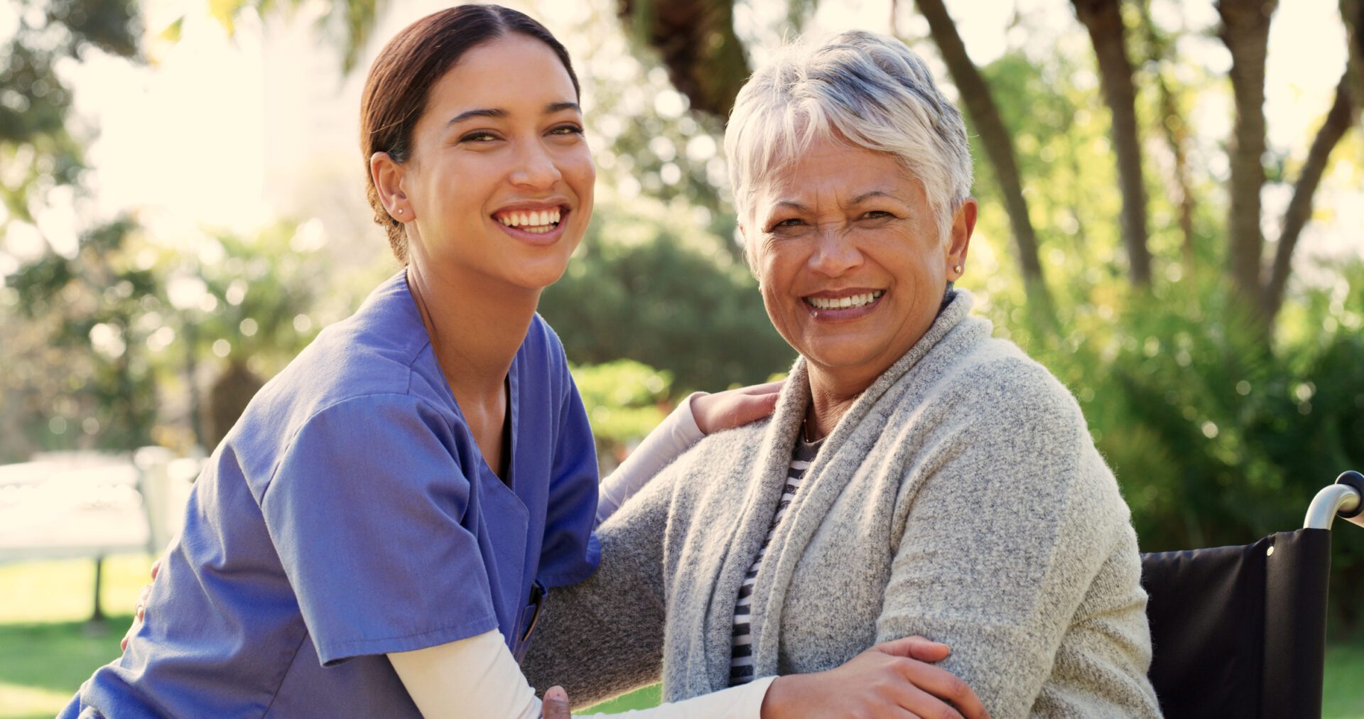 Caregiver smiling with elderly woman in wheelchair.