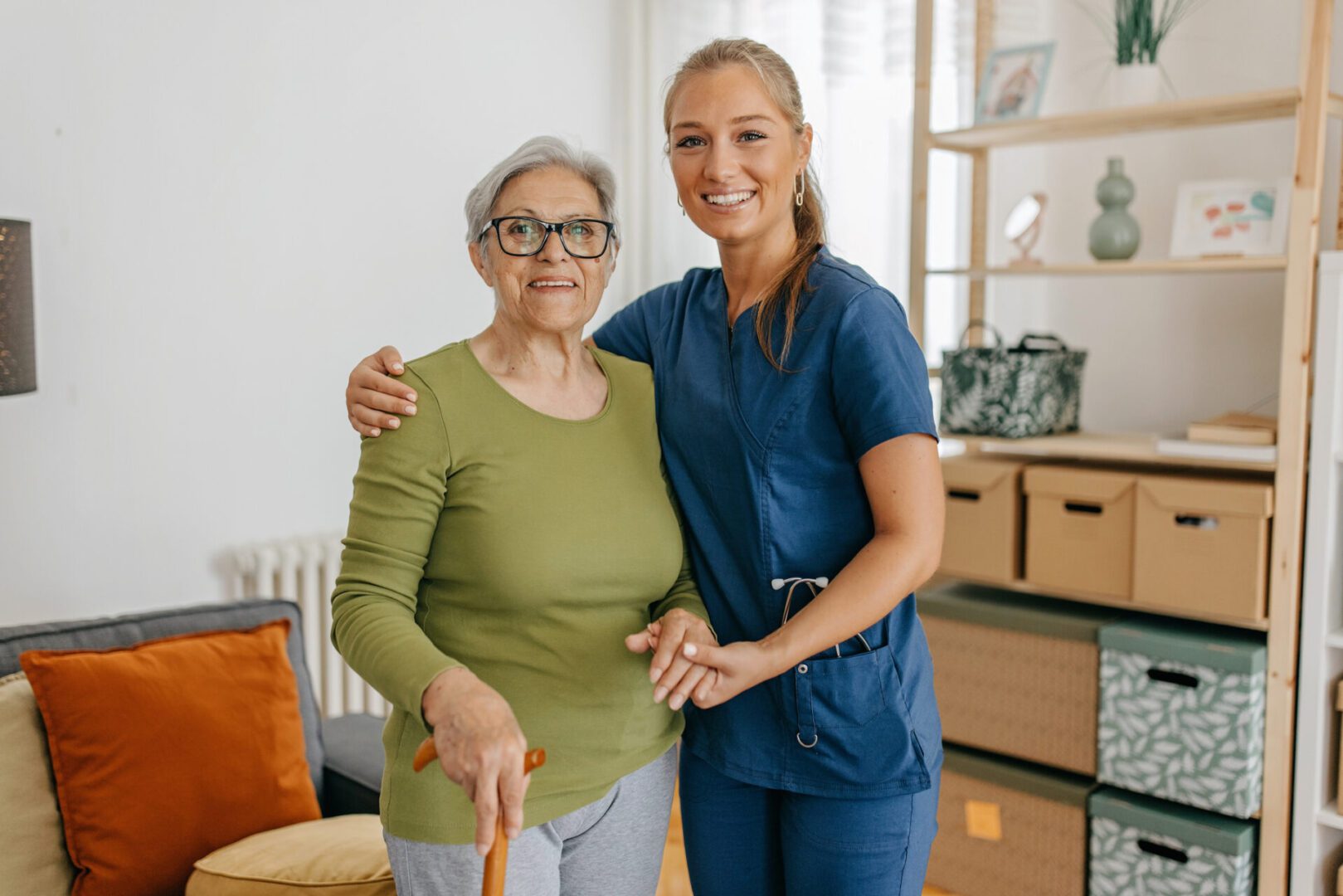 Caregiver hugging elderly woman with cane.