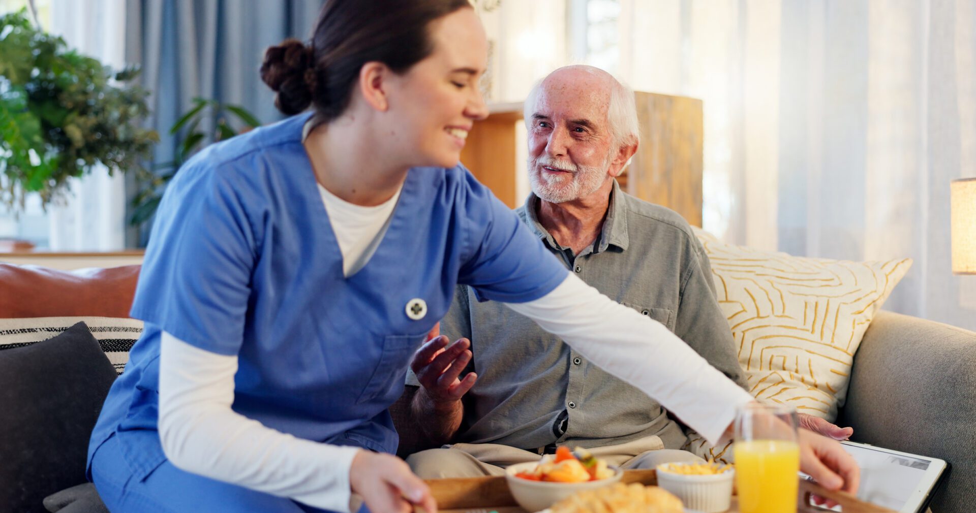 Caregiver serving breakfast to an elderly man.