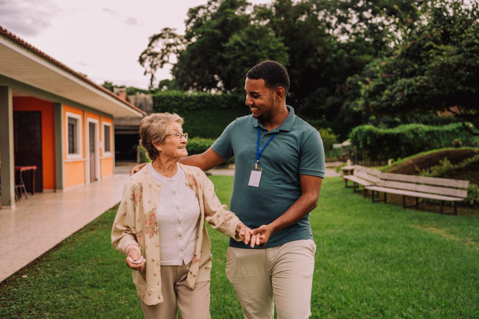 Caregiver walking with elderly woman outside.